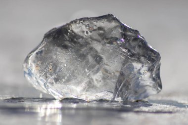 Güneşin altında eriyen donmuş parlak buz kübü soğuk kış mevsiminde kutup bölgesindeki şeffaf buzlarda hoş yansımalarla ısınan güneş ışığında ışıldayan buz kristallerinde suyu dondurur.