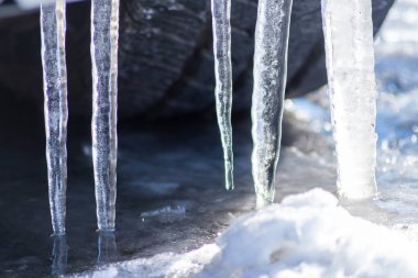 Uzun buz sarkıtları, kışın kentsel sürüş sorunları için aşırı düşük sıcaklıktaki kar fırtınasından sonra lastik gösterisiyle kaygan caddelerde asılı duruyor.