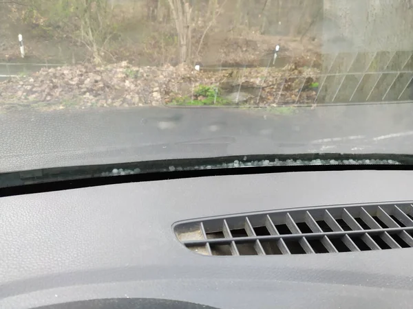 Iced hail on windshield shows risk of accident and the need of a car insurance with clear sight in winter, autumn and fall against dangerous driving with car destruction due to hail damage danger