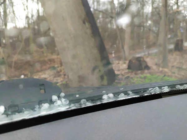 Iced hail on windshield shows risk of accident and the need of a car insurance with clear sight in winter, autumn and fall against dangerous driving with car destruction due to hail damage danger