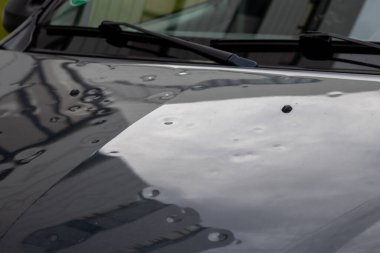 Dolu hasarı olan araba motoru kaputu, doğa gücünü, araba sigortasının önemini ve dolu fırtınalarına ve fırtına tehlikelerine karşı yeni bir değer sigortasını gösterir.