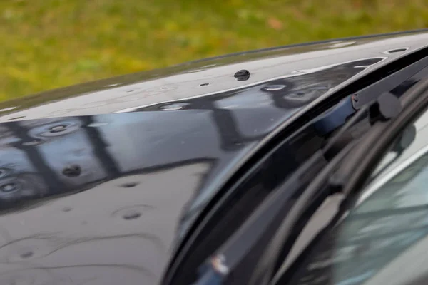 Car engine hood with many hail damage dents show the forces of nature and the importance of car insurance and a replacement value insurance against hail storm and storm hazards or extreme weather