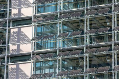 Sustainable cooling mechanism with solar panels and photovoltaic electricity generation as sun blind at the clean window facade of a modern skyscraper as economical architecture with solar cells panel