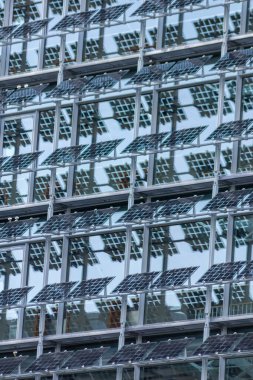 Sustainable cooling mechanism with solar panels and photovoltaic electricity generation as sun blind at the clean window facade of a modern skyscraper as economical architecture with solar cells panel