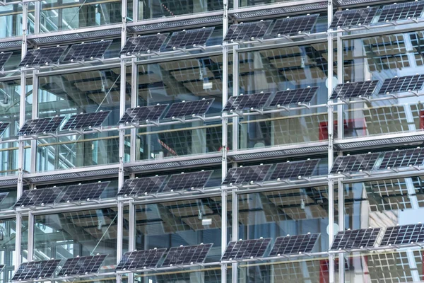 Sustainable cooling mechanism with solar panels and photovoltaic electricity generation as sun blind at the clean window facade of a modern skyscraper as economical architecture with solar cells panel