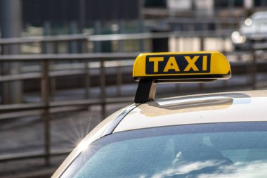 Taxi with yellow sign on roof on a shiny day waiting for passengers and tourists to drive to airport or home as flexible transportation in urban cities and streets on journeys and European mobility