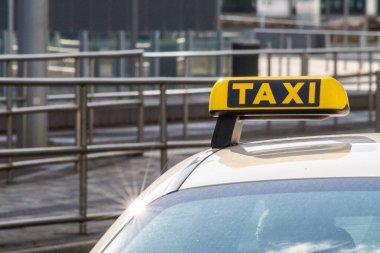 Taxi with yellow sign on roof on a shiny day waiting for passengers and tourists to drive to airport or home as flexible transportation in urban cities and streets on journeys and European mobility