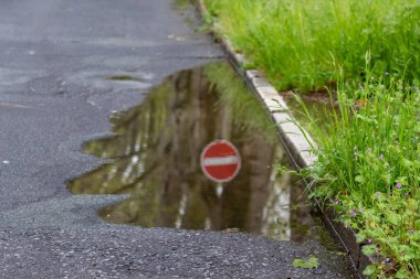Tek yönlü Alman yol işareti ve yasak yön olarak arabalar ve yol trafiği için yasak ve kısıtlama, boş yollarda sağanak yağmurun ardından bir su birikintisinin su yüzeyinde hoş bir yansıma.