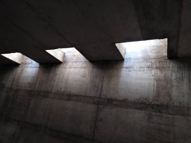 Metal bir ızgaradan güneş ışığı alan karanlık havalandırma boşluğu bodrum katı için beton hava yolu ve sanayi ve mimari için temiz hava ve havalandırma boruları sağlayan büyük tesisler gösteriyor.