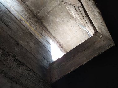Metal bir ızgaradan güneş ışığı alan karanlık havalandırma boşluğu bodrum katı için beton hava yolu ve sanayi ve mimari için temiz hava ve havalandırma boruları sağlayan büyük tesisler gösteriyor.