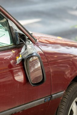 Araba kazası, vandalizm yaralanması ve kaçma sonucu sigorta kaybı gibi yıkık bir arabada asılı duran kırık bir yan ayna, şehirlerde tehlikeli trafik ve güvenlik sigortasına ihtiyaç olduğunu gösteriyor.