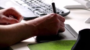Ana ofiste ergonomik klavye ile çizim ve çizim için serbest çalışan ve tasarımcı olarak grafik tablet kullanan erkek eller, iş yerinde ve masaüstünde ilham ve modern multimedya ekipmanları gösteriyor