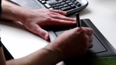 Ana ofiste ergonomik klavye ile çizim ve çizim için serbest çalışan ve tasarımcı olarak grafik tablet kullanan erkek eller, iş yerinde ve masaüstünde ilham ve modern multimedya ekipmanları gösteriyor