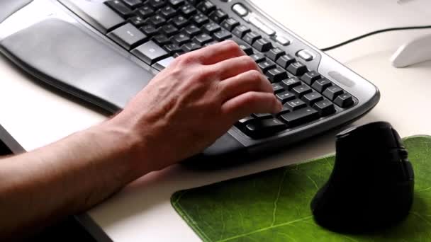 人間工学に基づいたキーボードを入力するビジネスマンまたはプロのプログラマー自宅のオフィスの職場で人間工学に基づいたマウスを使用してヨーロッパの男性の手で自宅から現代のコンピュータ機器を閉じる — ストック動画