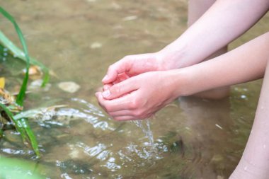 Küçük bir derede temiz suyla oynayan genç bir çocuk ellerini ve su kaynağını kullanarak ellerini soğutuyor ve Zen meditasyonu ya da çevreyi korumak için saf yaşam iksiriyle ferahlatıyor.