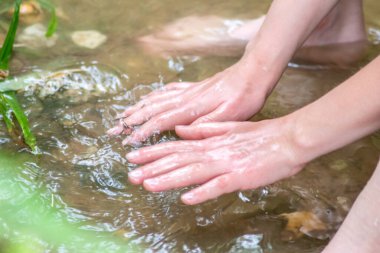 Küçük bir derede temiz suyla oynayan genç bir çocuk ellerini ve su kaynağını kullanarak ellerini soğutuyor ve Zen meditasyonu ya da çevreyi korumak için saf yaşam iksiriyle ferahlatıyor.