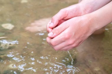 Küçük bir derede temiz suyla oynayan genç bir çocuk ellerini ve su kaynağını kullanarak ellerini soğutuyor ve Zen meditasyonu ya da çevreyi korumak için saf yaşam iksiriyle ferahlatıyor.