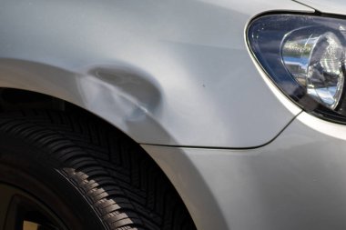 Dented car wing and fender with scratches and bumps after crash and car accident with hit-and-run driving and absconding shows need for car insurance and safety protection and mechanics garage service