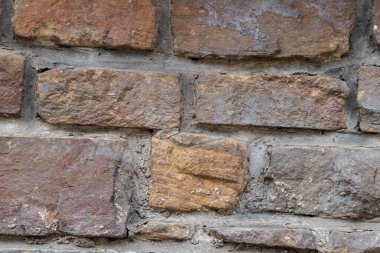 Kale duvarı gibi pürüzlü taşlarla kaplı büyük bir duvar, farklı tuğlalar, doğal arka plan ve kayalık antik zamanların duvarı, granit mineraller için eski dokular olarak taş gibi katı tuğlalar gösteriyor.