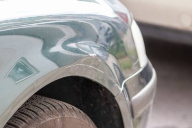 Dented car wing and fender with scratches and bumps after crash and car accident with hit-and-run driving and absconding shows need for car insurance and safety protection and mechanics garage service