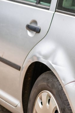 Dented car wing and fender with scratches and bumps after crash and car accident with hit-and-run driving and absconding shows need for car insurance and safety protection and mechanics garage service