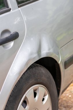 Dented car wing and fender with scratches and bumps after crash and car accident with hit-and-run driving and absconding shows need for car insurance and safety protection and mechanics garage service