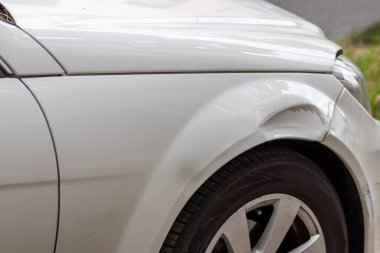 Dented car wing and fender with scratches and bumps after crash and car accident with hit-and-run driving and absconding shows need for car insurance and safety protection and mechanics garage service