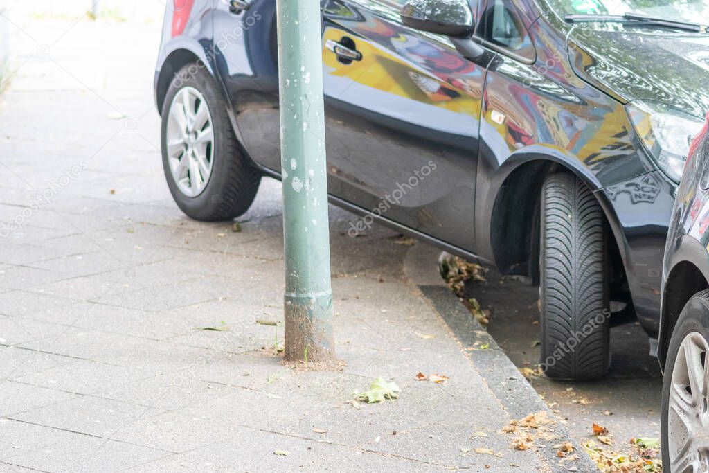 Badly parked car with tire on pavement shows wheel on walkway as traffic violation with penalty for poor driving and parking violation in urban streets with danger for pedestrians by selfish drivers