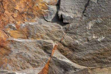 Turuncu renkte çiğ kaya, mineraller ve metaller doğal taşlardır. Arka planda sert bir sahil veya kayalık sahilde ezilmiş ve sert malzemeler vardır. Taş ocakları ve kumtaşları kırık yüzey granitleri şeklinde gösterirler.