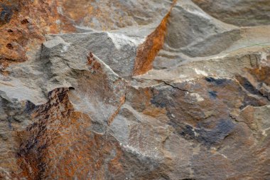 Turuncu renkte çiğ kaya, mineraller ve metaller doğal taşlardır. Arka planda sert bir sahil veya kayalık sahilde ezilmiş ve sert malzemeler vardır. Taş ocakları ve kumtaşları kırık yüzey granitleri şeklinde gösterirler.