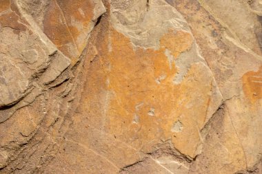Turuncu renkte çiğ kaya, mineraller ve metaller doğal taşlardır. Arka planda sert bir sahil veya kayalık sahilde ezilmiş ve sert malzemeler vardır. Taş ocakları ve kumtaşları kırık yüzey granitleri şeklinde gösterirler.
