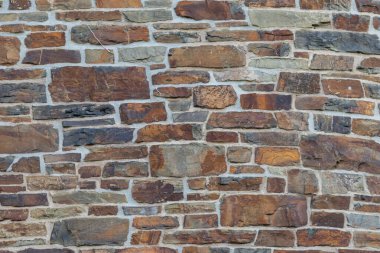 Kale duvarı gibi pürüzlü taşlarla kaplı büyük bir duvar, farklı tuğlalar, doğal arka plan ve kayalık antik zamanların duvarı, granit mineraller için eski dokular olarak taş gibi katı tuğlalar gösteriyor.