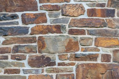 Kale duvarı gibi pürüzlü taşlarla kaplı büyük bir duvar, farklı tuğlalar, doğal arka plan ve kayalık antik zamanların duvarı, granit mineraller için eski dokular olarak taş gibi katı tuğlalar gösteriyor.