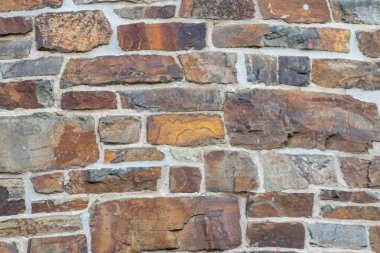 Kale duvarı gibi pürüzlü taşlarla kaplı büyük bir duvar, farklı tuğlalar, doğal arka plan ve kayalık antik zamanların duvarı, granit mineraller için eski dokular olarak taş gibi katı tuğlalar gösteriyor.