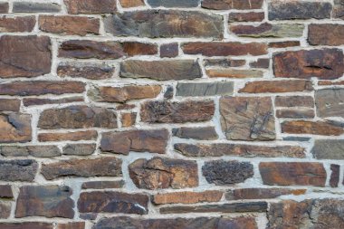 Kale duvarı gibi pürüzlü taşlarla kaplı büyük bir duvar, farklı tuğlalar, doğal arka plan ve kayalık antik zamanların duvarı, granit mineraller için eski dokular olarak taş gibi katı tuğlalar gösteriyor.