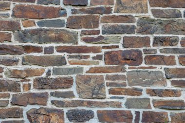 Kale duvarı gibi pürüzlü taşlarla kaplı büyük bir duvar, farklı tuğlalar, doğal arka plan ve kayalık antik zamanların duvarı, granit mineraller için eski dokular olarak taş gibi katı tuğlalar gösteriyor.