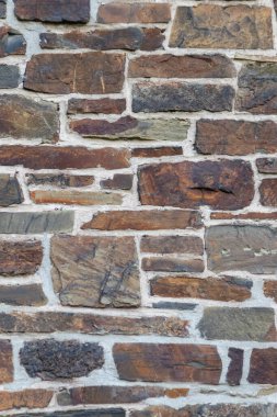 Kale duvarı gibi pürüzlü taşlarla kaplı büyük bir duvar, farklı tuğlalar, doğal arka plan ve kayalık antik zamanların duvarı, granit mineraller için eski dokular olarak taş gibi katı tuğlalar gösteriyor.