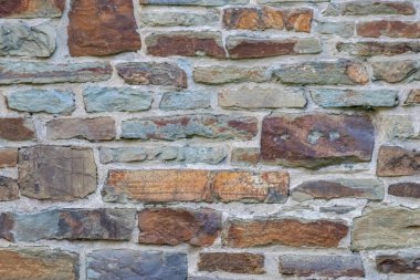 Kale duvarı gibi pürüzlü taşlarla kaplı büyük bir duvar, farklı tuğlalar, doğal arka plan ve kayalık antik zamanların duvarı, granit mineraller için eski dokular olarak taş gibi katı tuğlalar gösteriyor.