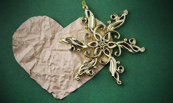 Heart with a gold snowflake on a green background. New Year\'s baubles.