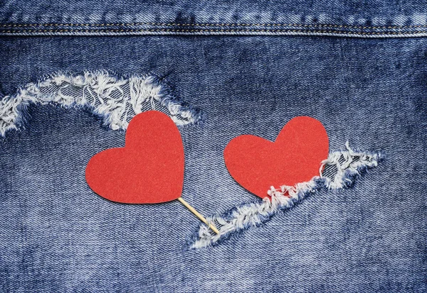 Red hearts on denim. Love symbol. Valentine\'s card. Ripped jeans with hearts.