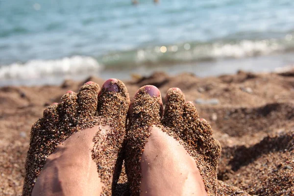 Women\'s feet in the sea sand. Dirty feet.