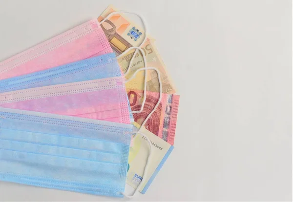 Medical masks and euro banknotes on a light background.