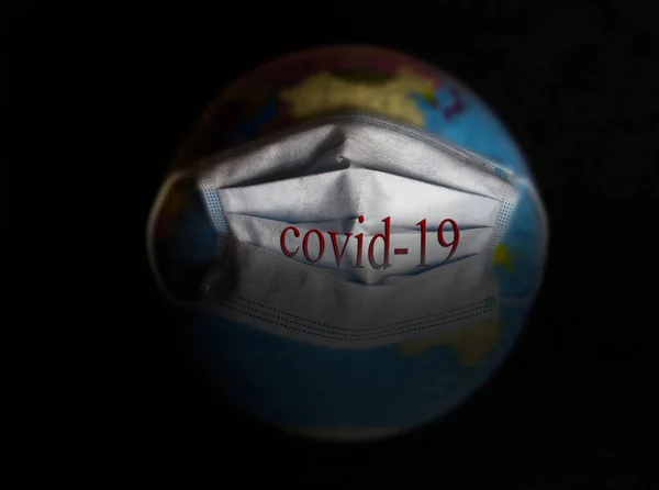 Globe in a medical mask. Planet Earth. Globe. The inscription on the mask covid-19.