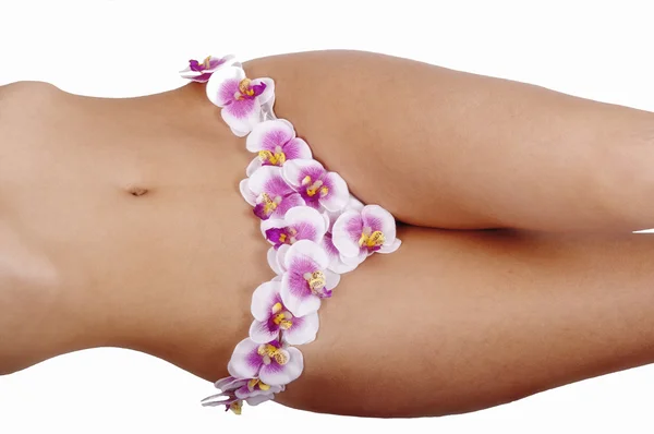 Beautiful feet of young girl in shorts with an orchid — Stock Photo, Image