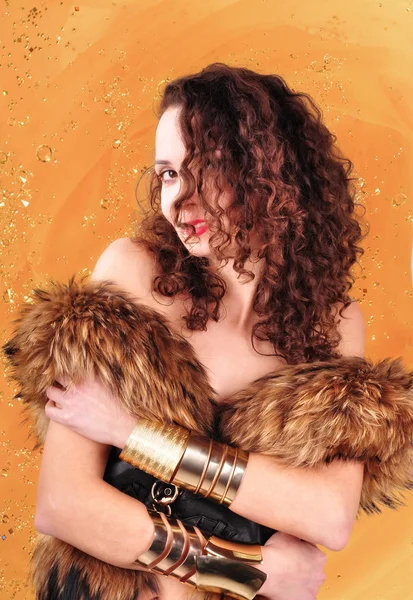 Young girl with curly hair in a fur coat on an abstract background — Stock Photo, Image
