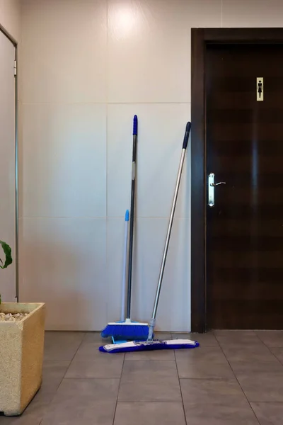 broom and mop in front of the toilet door. Cleaning service in restaurants and hotels. Cleaning employees