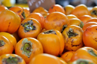 Bir market tezgahına yığılmış kakiler. Mevsim meyvesi. Doğal, ekolojik ve biyolojik ürünlerin yakınlığı. Alicante, İspanya.