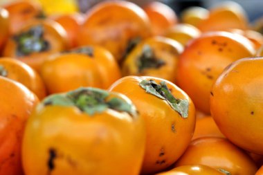 Bir market tezgahına yığılmış kakiler. Mevsim meyvesi. Doğal, ekolojik ve biyolojik ürünlerin yakınlığı. Alicante, İspanya.