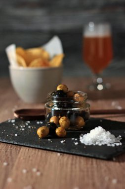 Bir kavanoz siyah ve yeşil zeytin, aromatik bitkilerle kaplı. Aperatifler, aperatifler ve turşularla dolu bir hayat. Yoğun tatlar