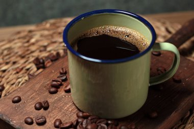 Sade kahveyle doldurulmuş ve kavrulmuş kahve çekirdekleri ile süslenmiş fincanın yakın çekimi. Kırsal tarzda gastronomik ve aşçılık fotoğrafçılığı